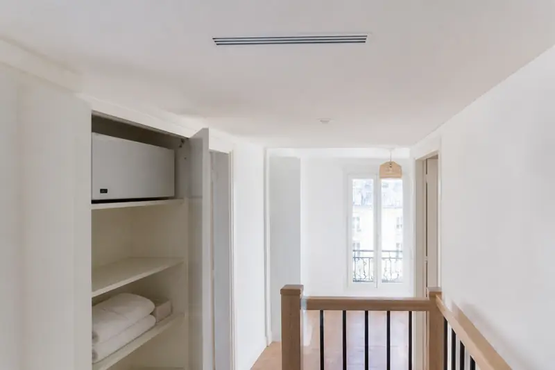 Unité de climatisation gainable installée dans un placard technique, gaines partant vers le plafond